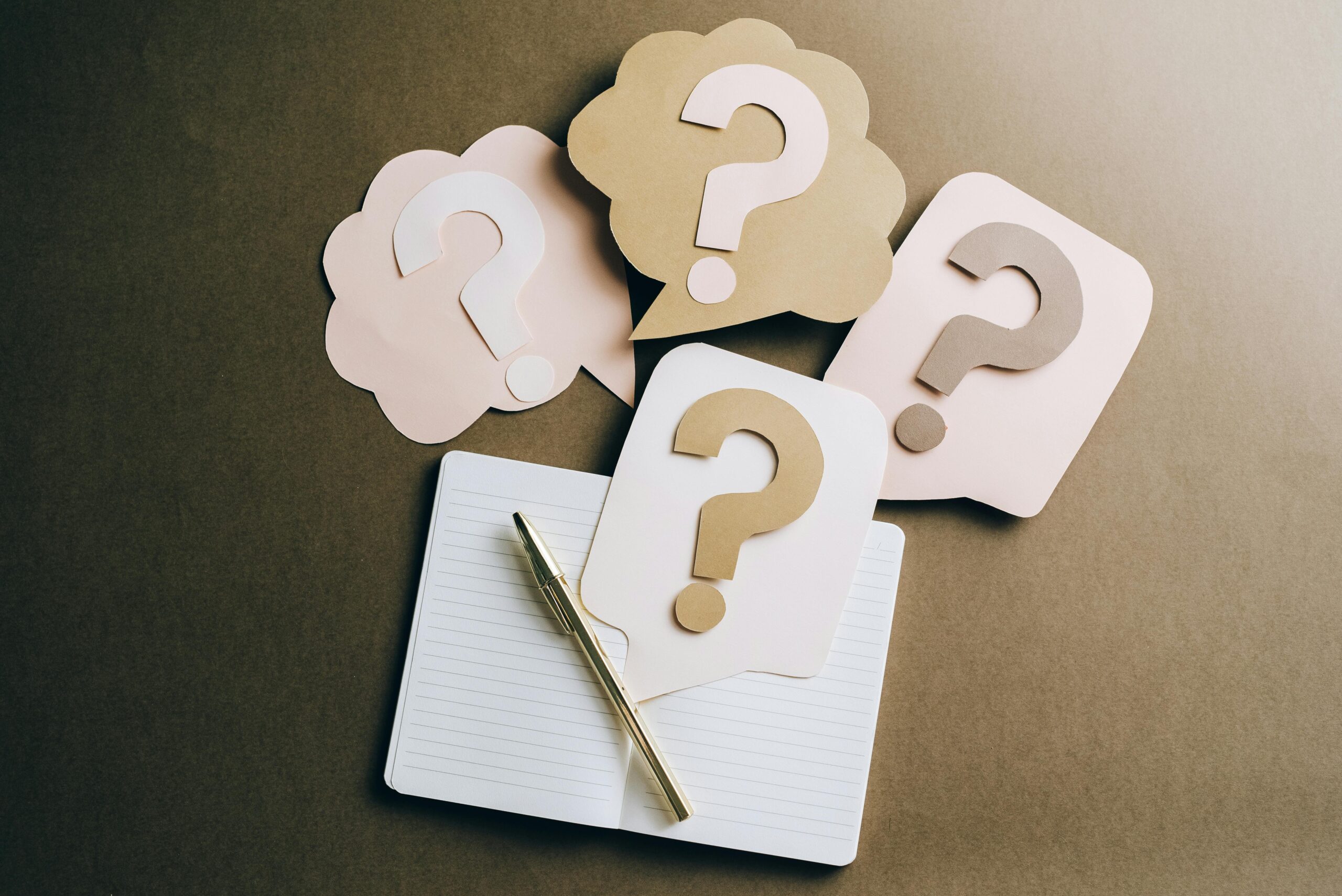 Illustration of question marks on paper above a notebook and pen, symbolizing confusion and decision-making in workplace politics.